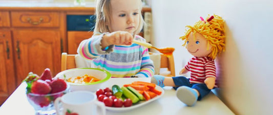 toddler girl feeding vegetables to her doll