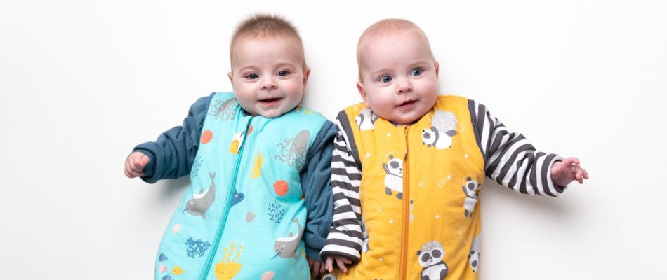 Twins in a blue and yellow baby sleeping bag