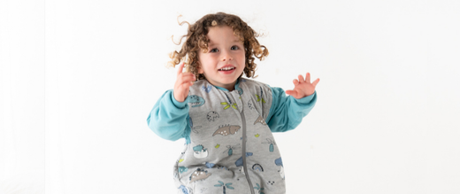 boy jumping in a dinosaur sleeping bag with feet