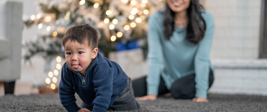 toddler crawling in front of a christmas tree