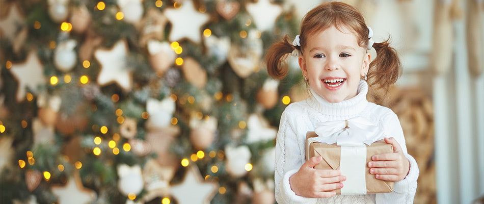 girl with present in front of the christmas tree