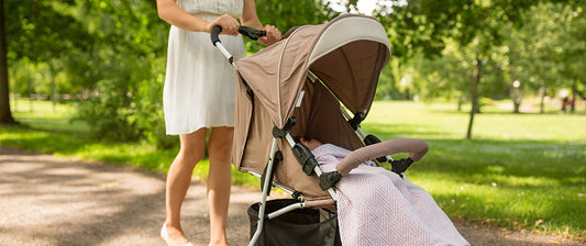 woman pushing pushchair with baby in the park