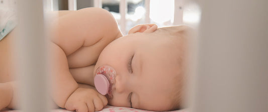 baby sleeping in cot with dummy