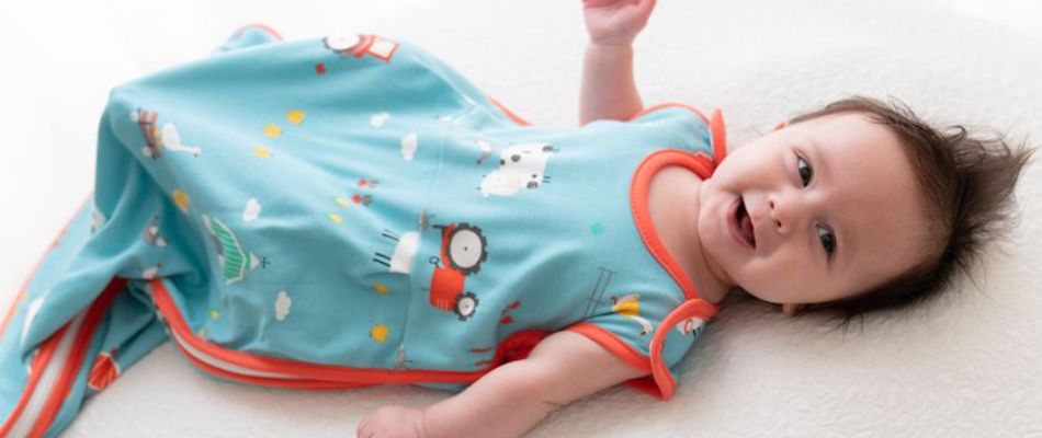 baby lying in bed in farmyard blue sleeping bag