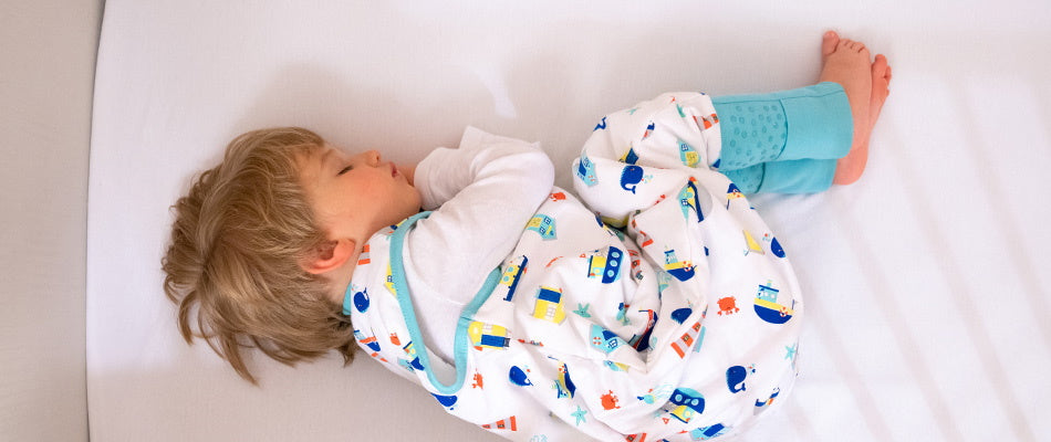 boy on bed sleeping in sleeping bag with feet